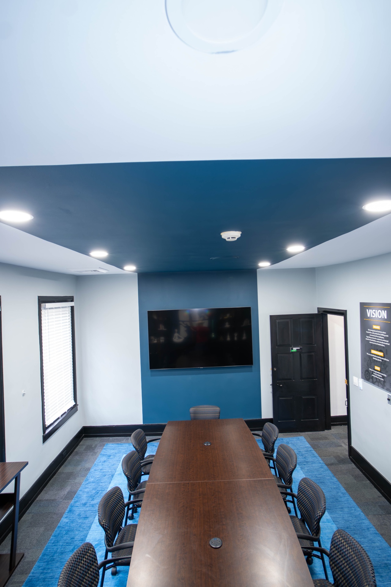 Boardroom with cobalt area rug and wall-mounted display