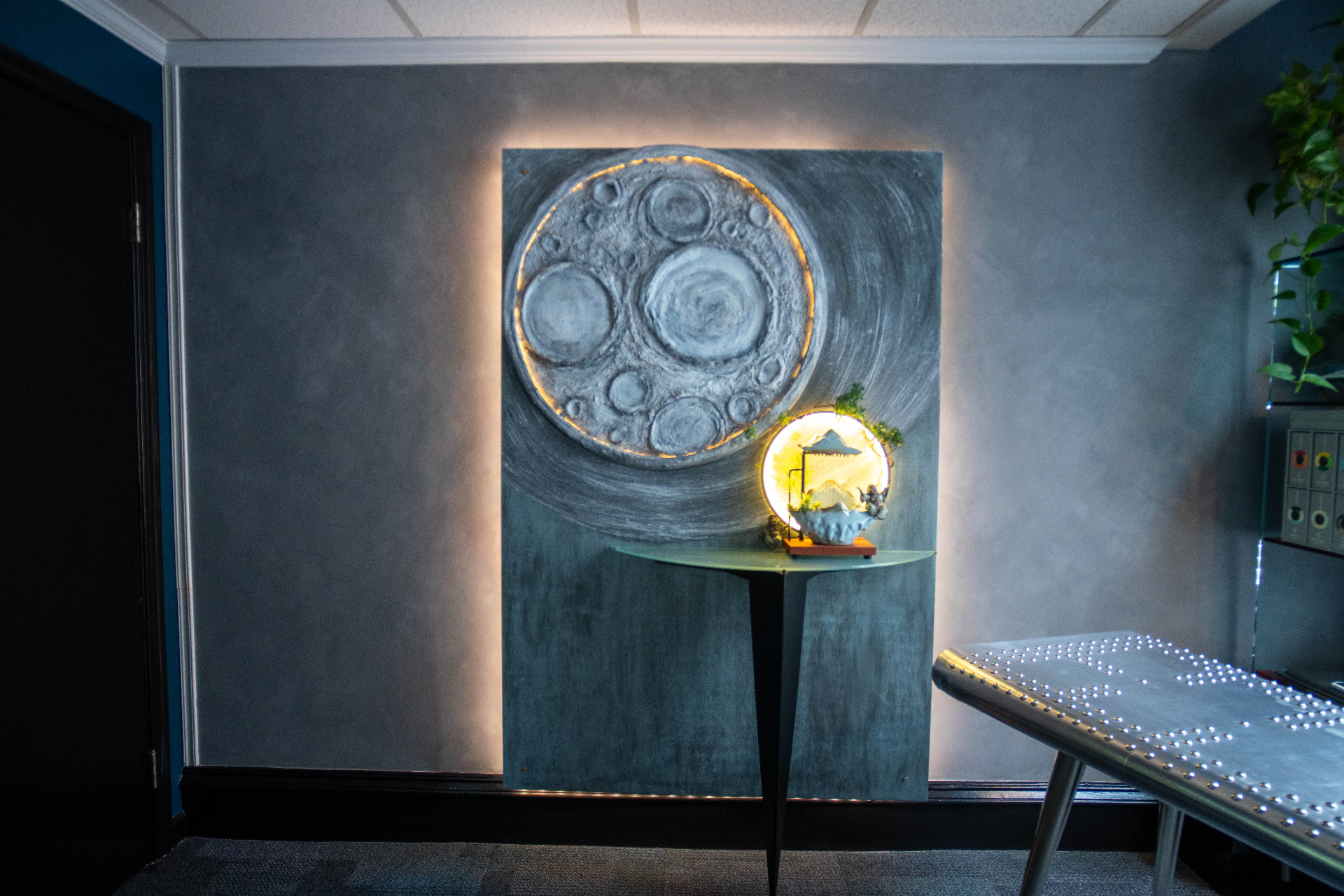 Sculptural moon and pagoda art installation on textured wall