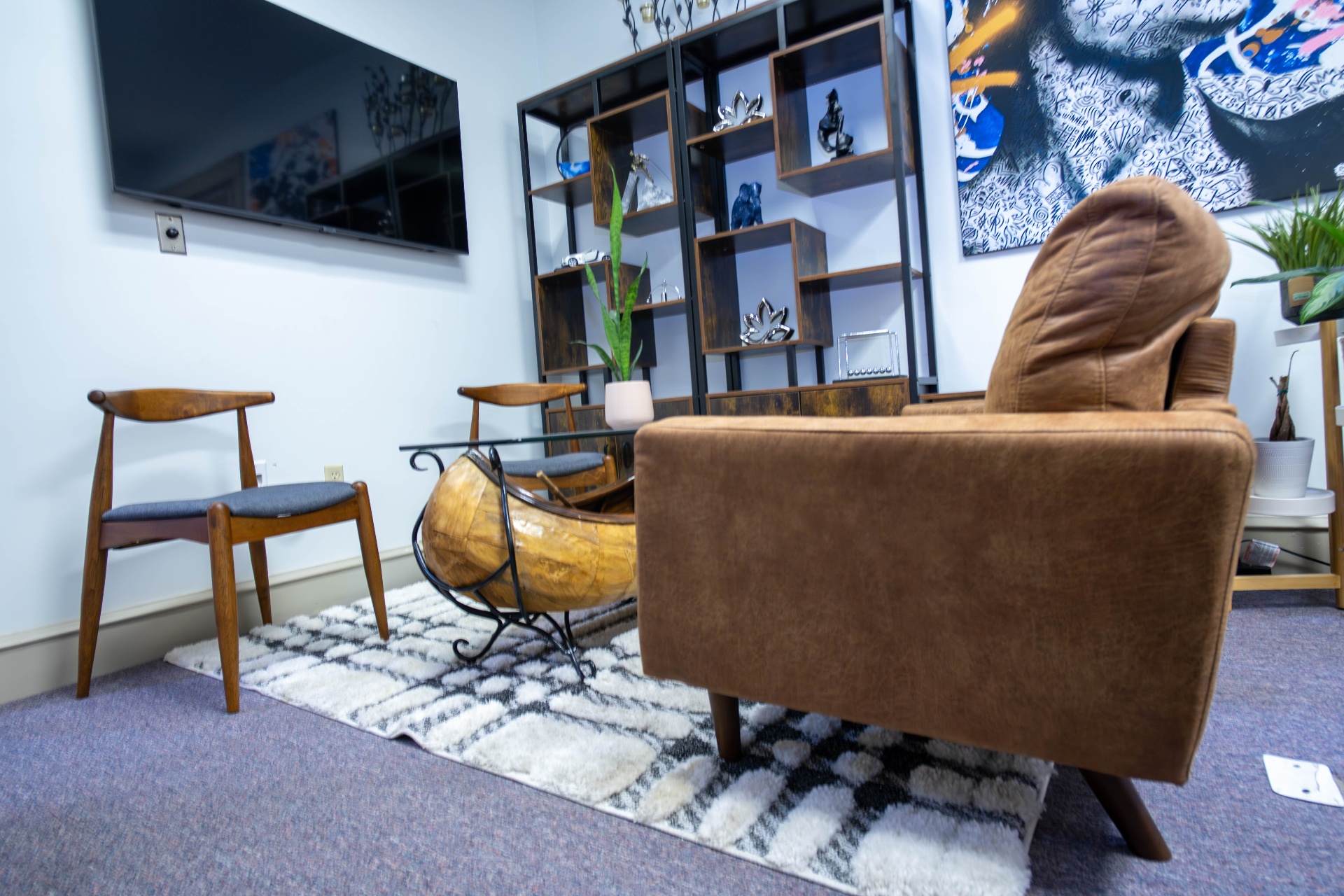Lounge with mid-century chairs, canoe coffee table, and pop-art canvas