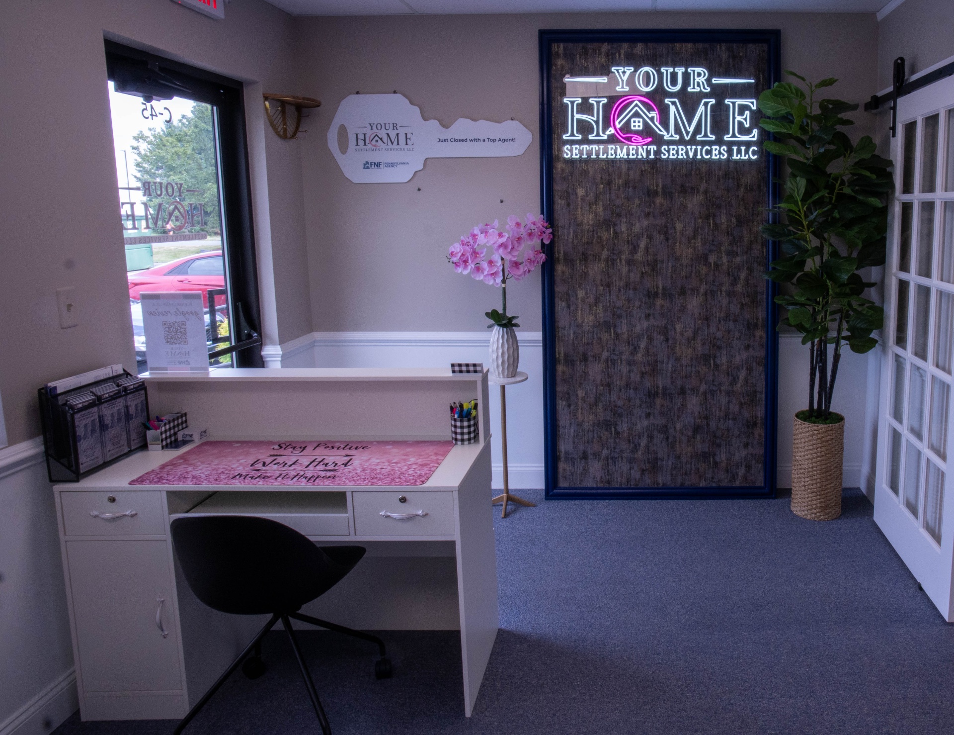 Front reception desk with neon-lit Your Home Settlement Services signage