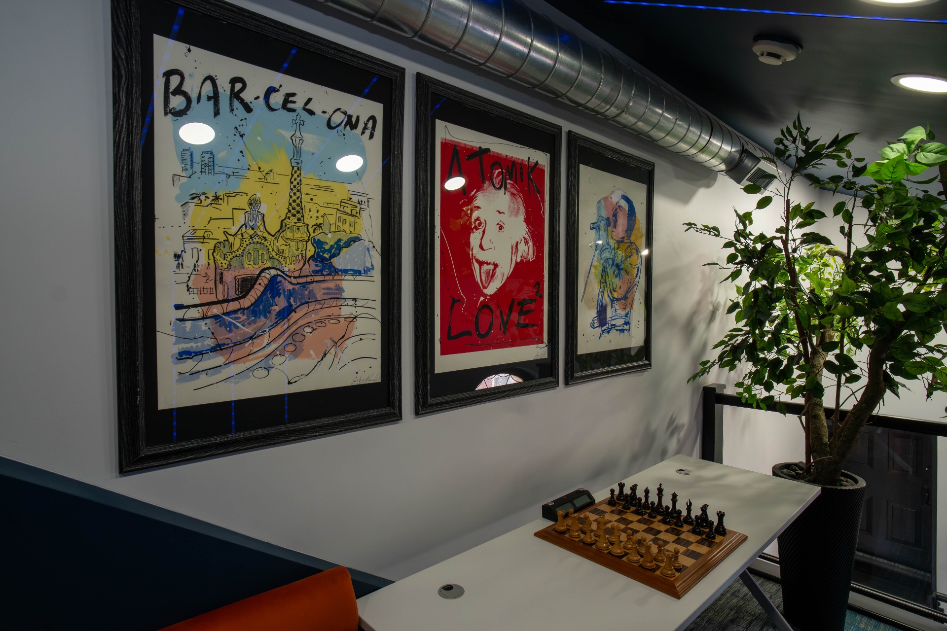 Framed Barcelona, Einstein, and figure prints over the chess nook