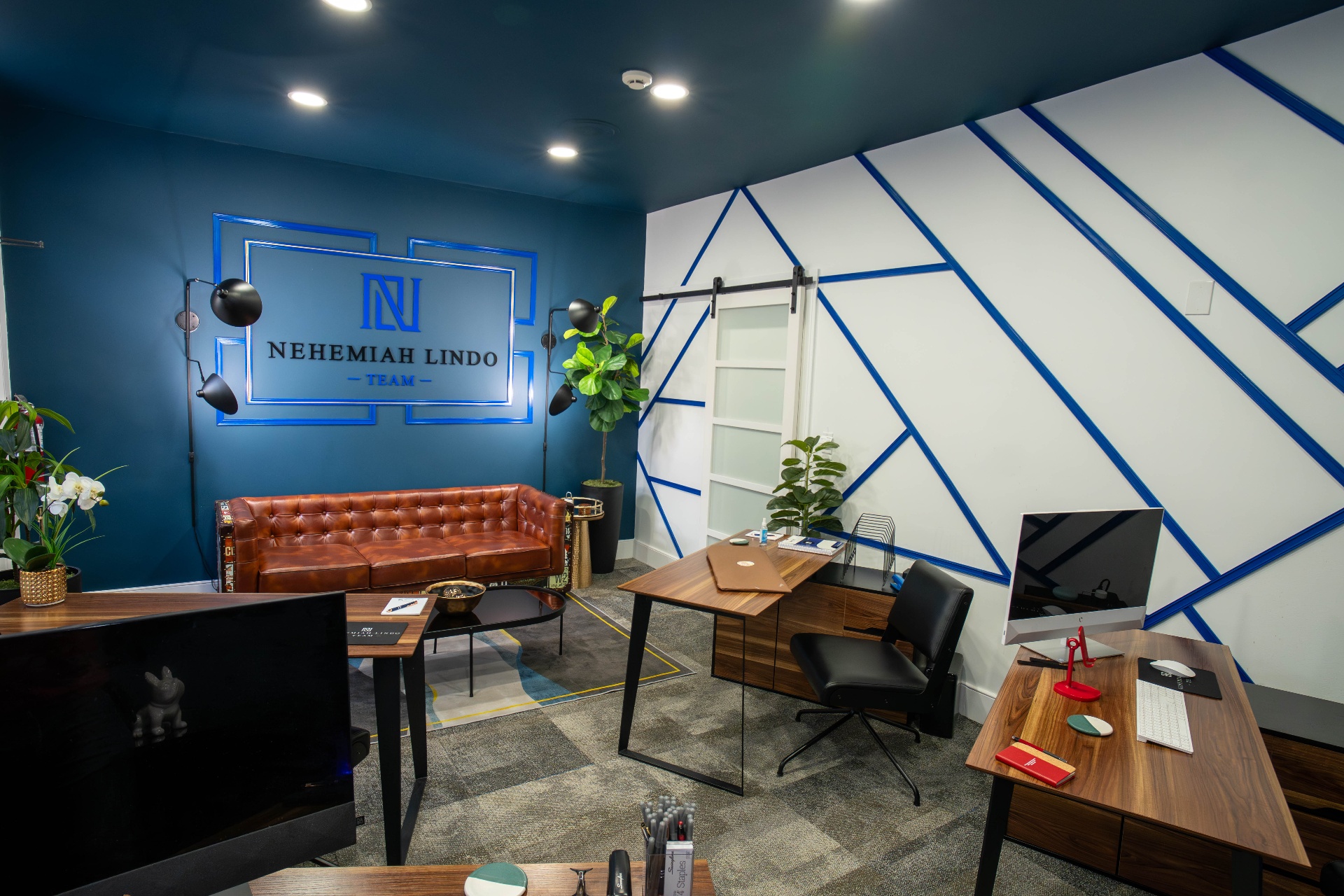 Nehemiah Lindo Team office with tufted leather sofa and geometric blue wall