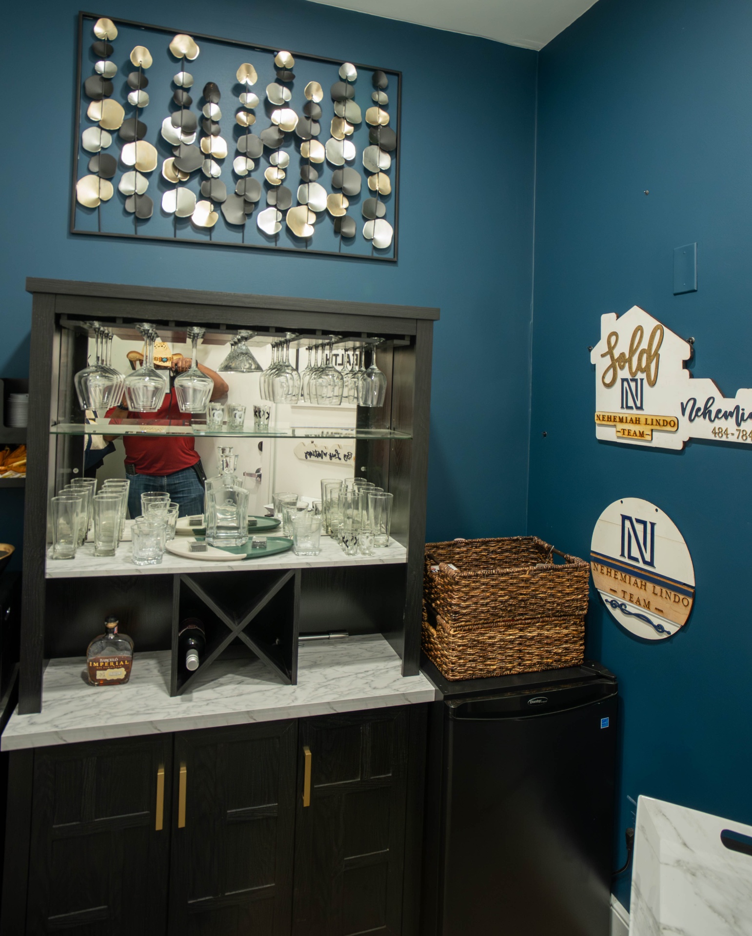 Bar nook with marble-top cabinetry, glassware, and metallic petal wall sculpture