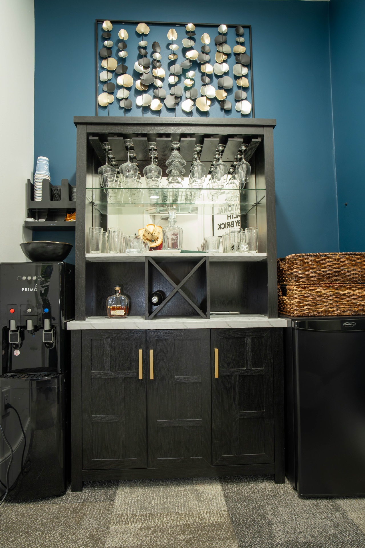 Refreshment station with dark bar cabinet, water dispenser, and metallic wall art