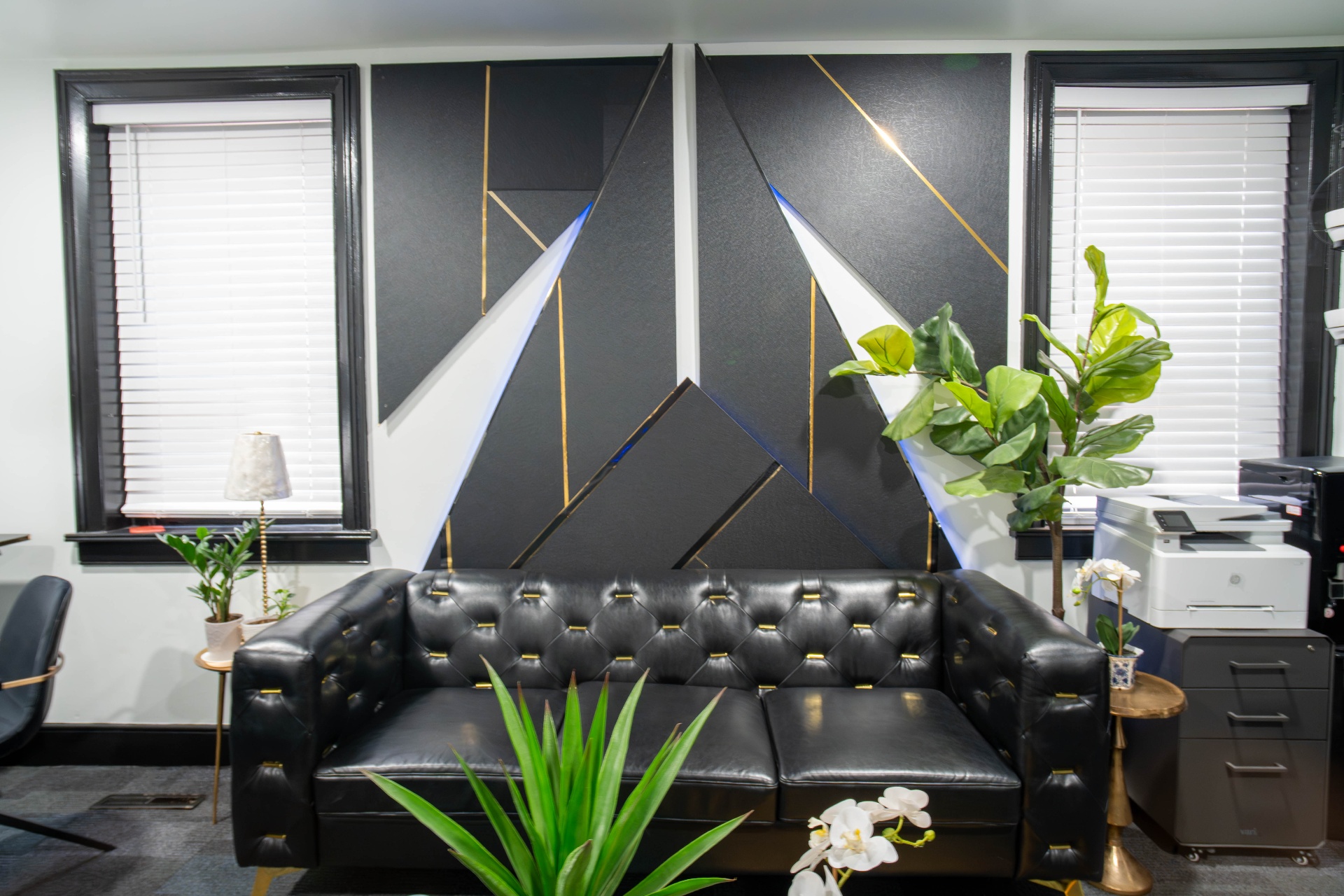 Executive lounge with tufted leather sofa and geometric black and gold accent wall