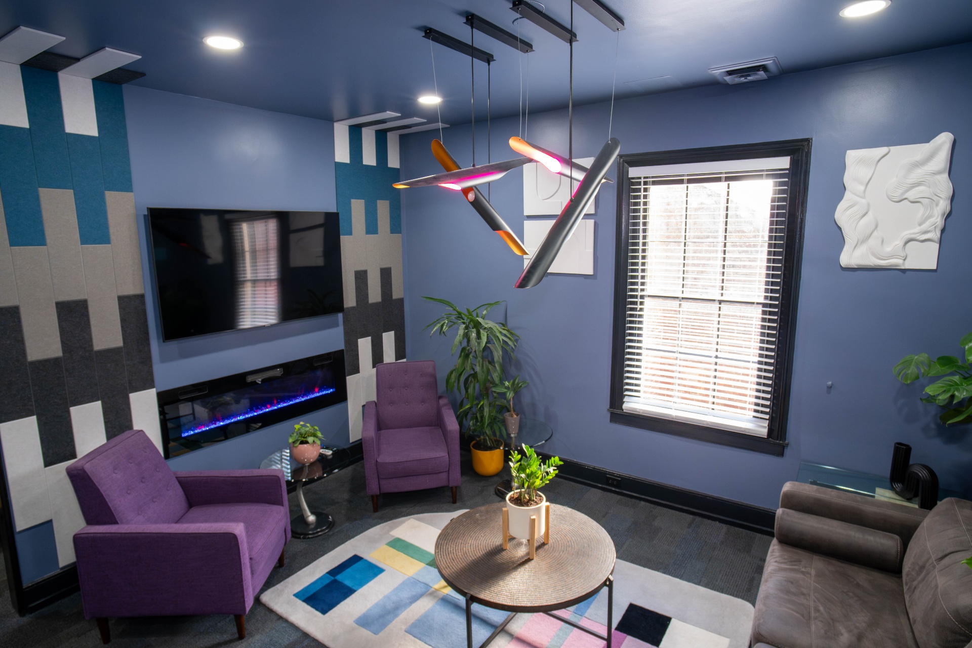 Periwinkle media lounge with fireplace, plaster wall reliefs, and modular pendant