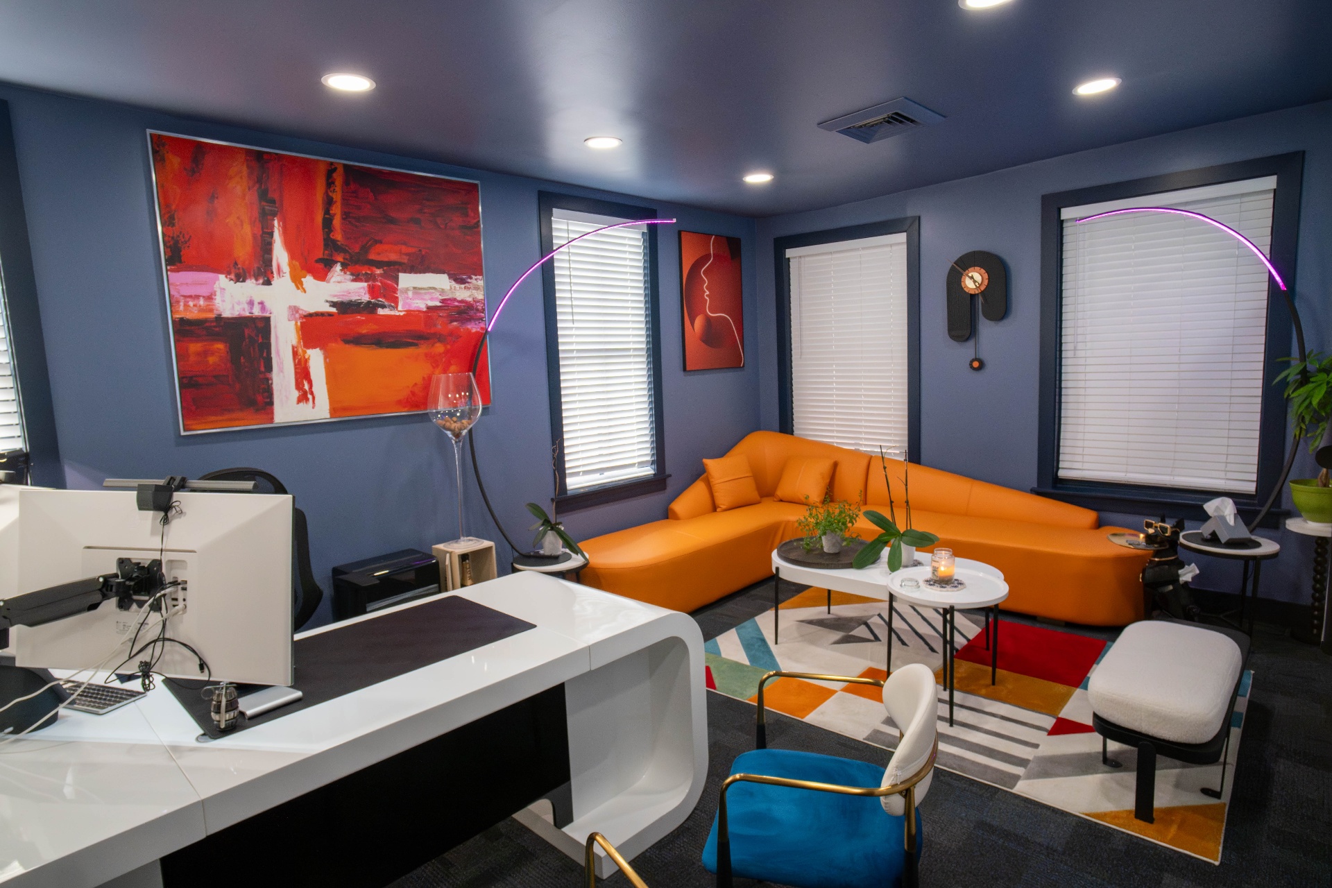 Executive office with orange curved sofa, red abstract artwork, and arc floor lamps